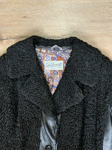 Kingspier Vintage - Salon Fernande Furs black persian wool coat with black leather trim details, four button closures down the front pockets and striking blue and bronze paisley lining with inside pockets. Made in Montreal.