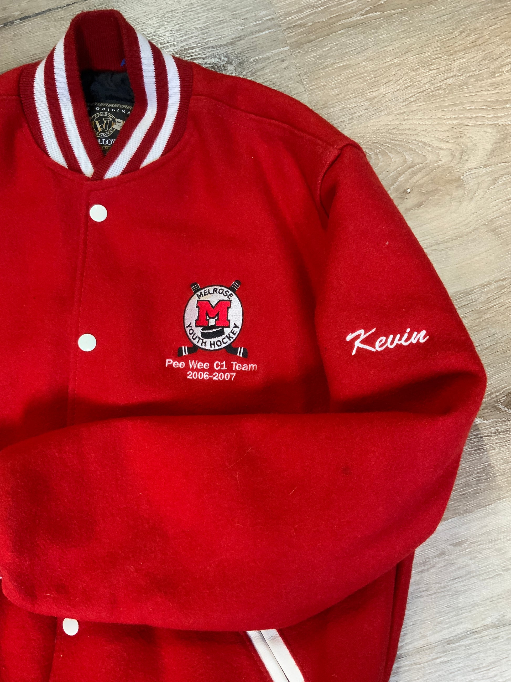 Kingspier Vintage - Melrose Youth Hockey letterman’s jacket in red with white accents, embroidered emblem on the front and lettering on the back with monogram on shoulder “Kevin”. Snap closures, slash pockets. Made in the USA. Size M.