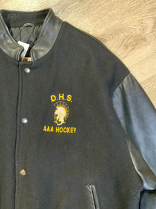 Kingspier Vintage - Dartmouth High School AAA Hockey letterman’s jacket in black with snap closures, slash pockets, quilted lining and embroidered team emblem. Made in Canada. Size XL.