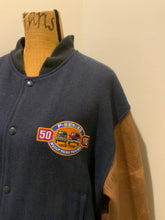Load image into Gallery viewer, Kingspier Vintage - Ford F-Series 50 year anniversary letterman’s jacket in navy with brown leather sleeves, snap closures, slash pockets and an inside pocket.
