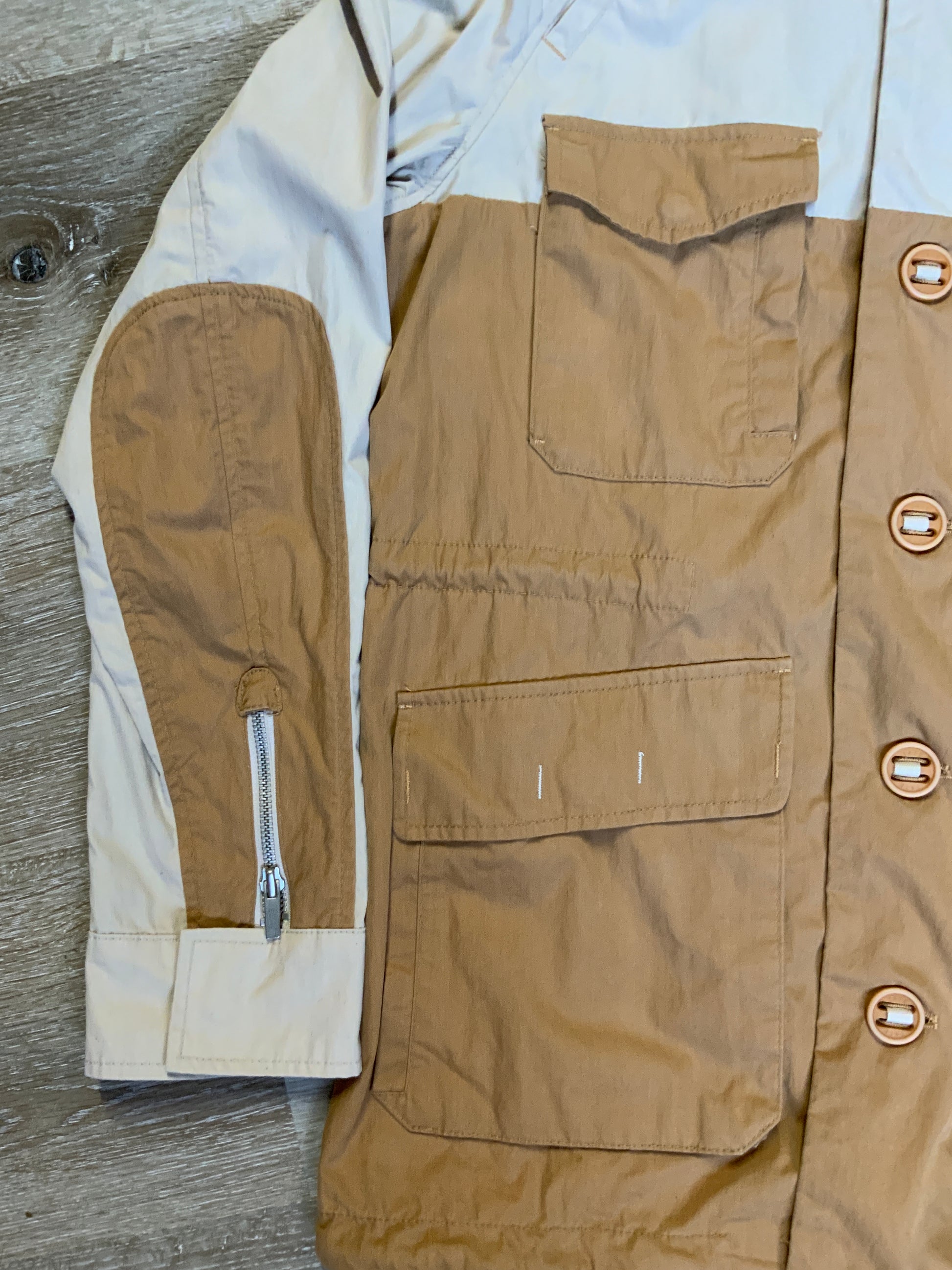 Kingspier Vintage - Tate beige and tan field jacket with hood, button closures, flap pockets, vent in the back, elbow patches and drawstring at the waist and the bottom hem. 