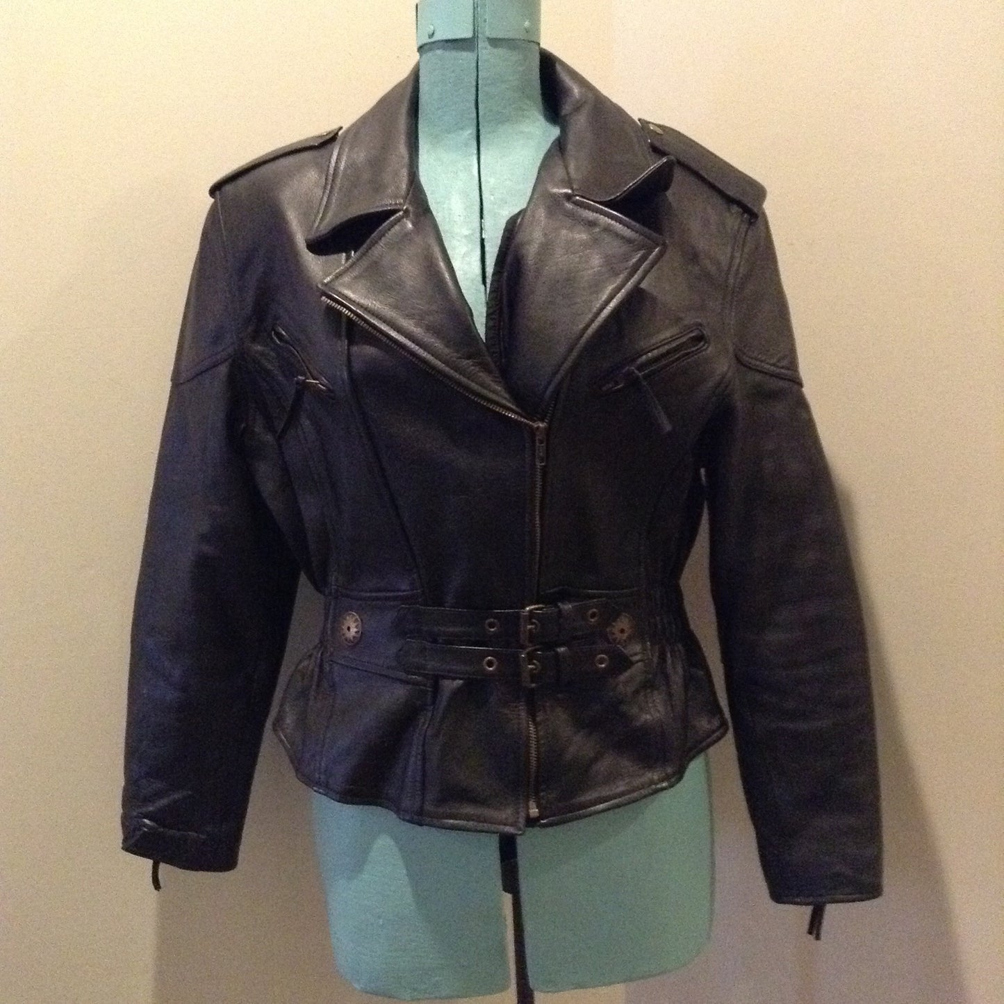 Kingspier Vintage -Vintage black leather moto jacket with brass hardware and zipper closure, belt details and a zipper reveals a vent in the back . Size large.
