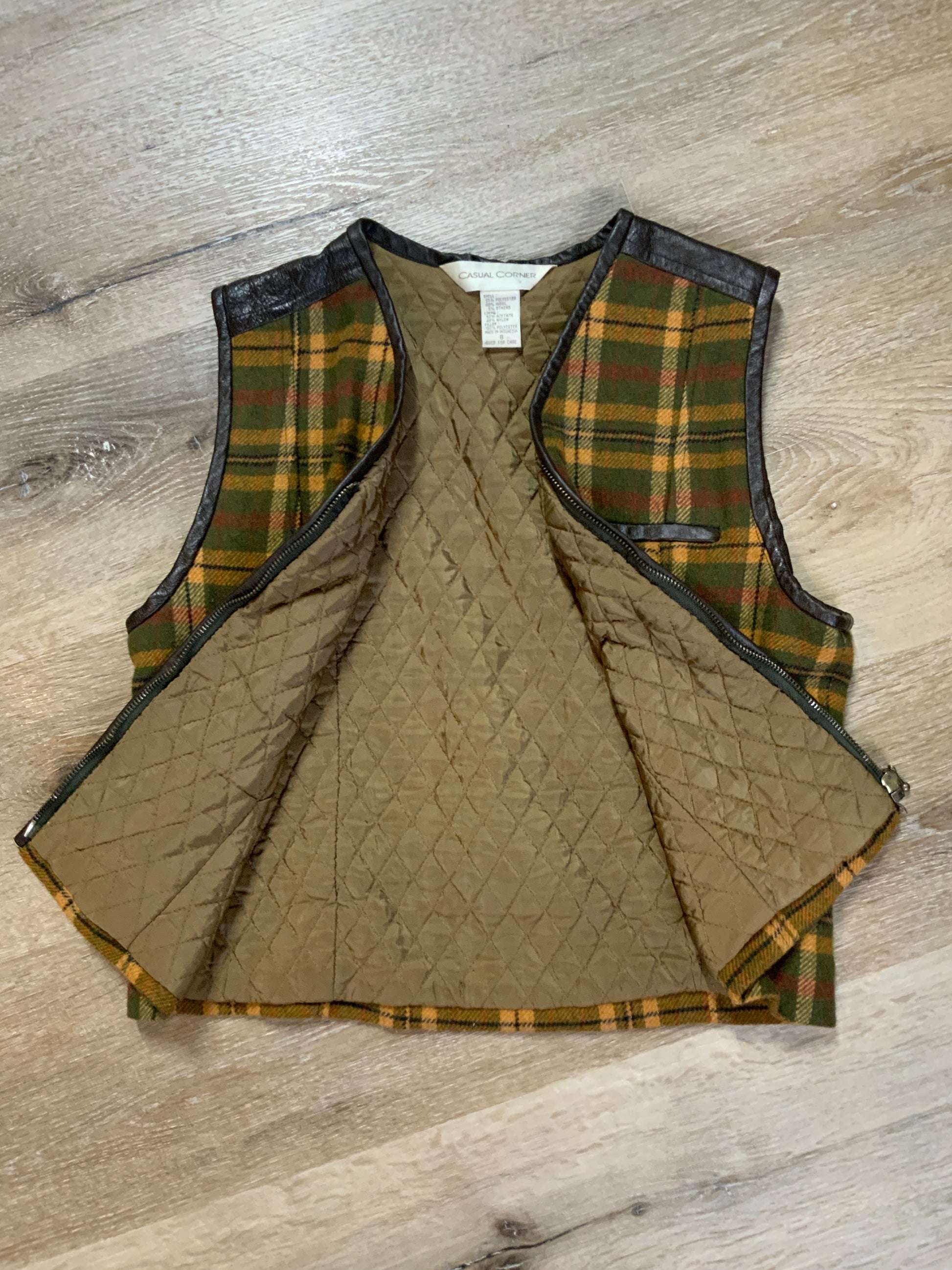 Kingspier Vintage - Casual Corner green plaid wool vest with leather trim and details, zipper closure, one zip pocket on the chest and a quilted lining. Size 8.