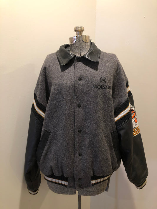 Kingspier Vintage - Fat Cat by Jazz grey and black wool varsity jacket with two large custom Jazz Golf embroidered patches on the arm and the back and Molson is embroidered on the chest in black, leather sleeves and collar, pockets, snap closures, knit details and a quilted lining. Made in Canada by Mondetta . Size XL.