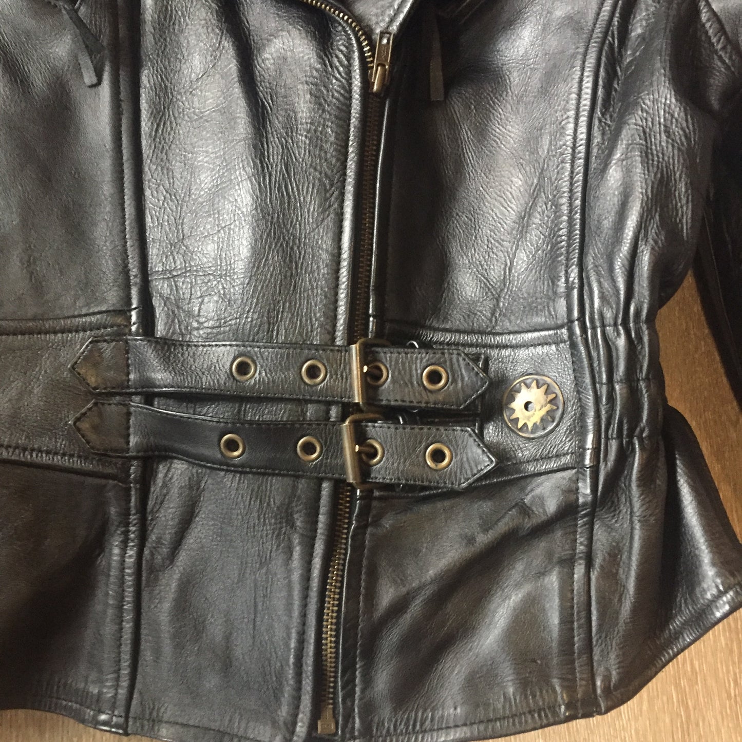 Kingspier Vintage -Vintage black leather moto jacket with brass hardware and zipper closure, belt details and a zipper reveals a vent in the back . Size large.
