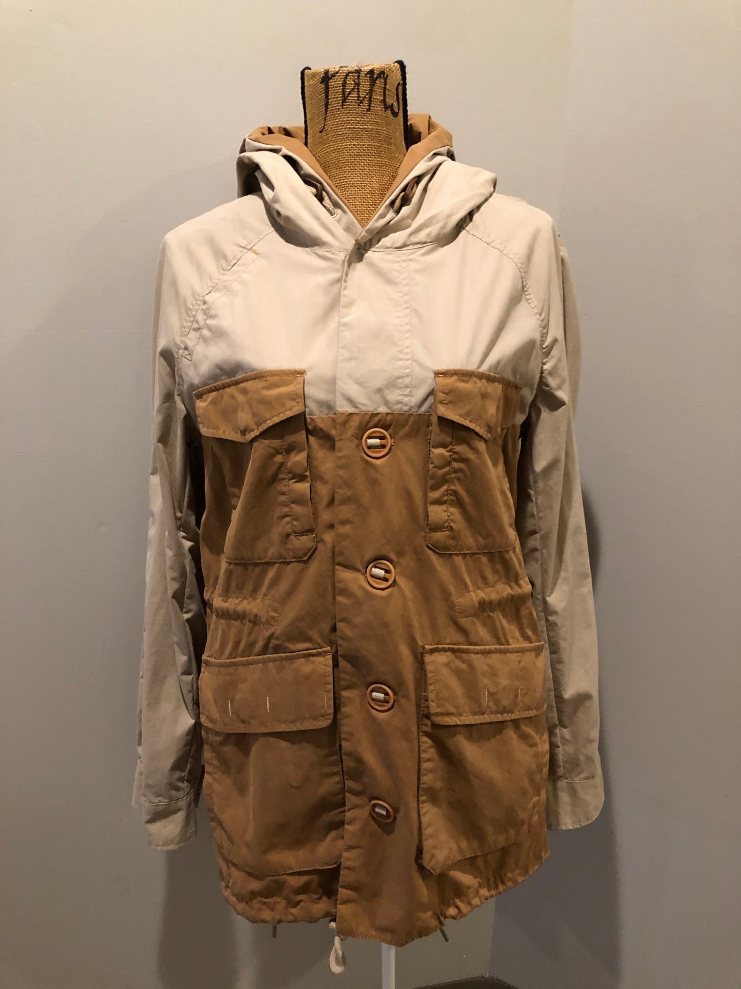 Kingspier Vintage - Tate beige and tan field jacket with hood, button closures, flap pockets, vent in the back, elbow patches and drawstring at the waist and the bottom hem. 