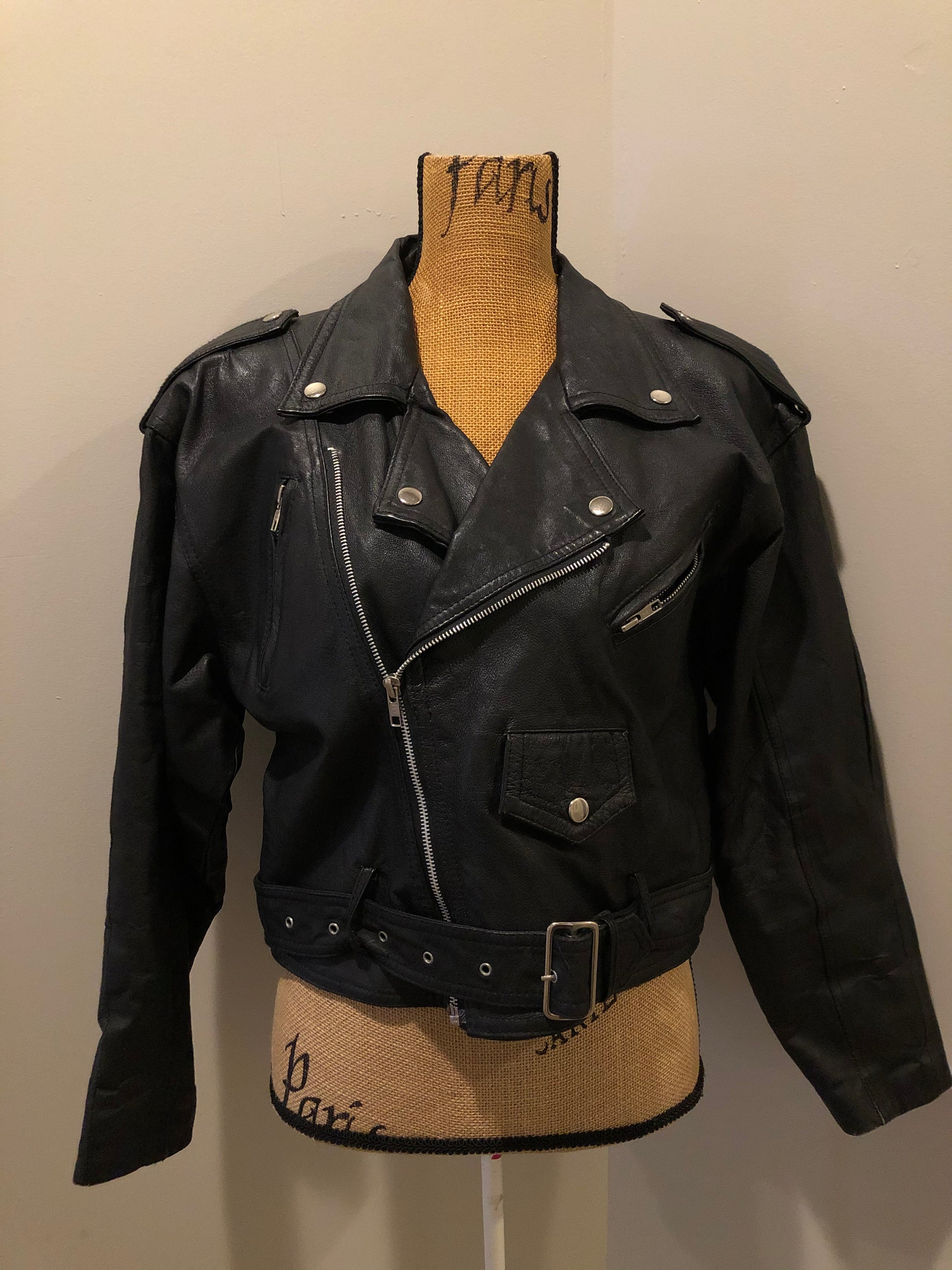 Kingspier Vintage - Cosa Nova black leather motorcycle jacket with two slash pockets, one flap pocket and a belt at the waist. Made in Canada. Size large. 