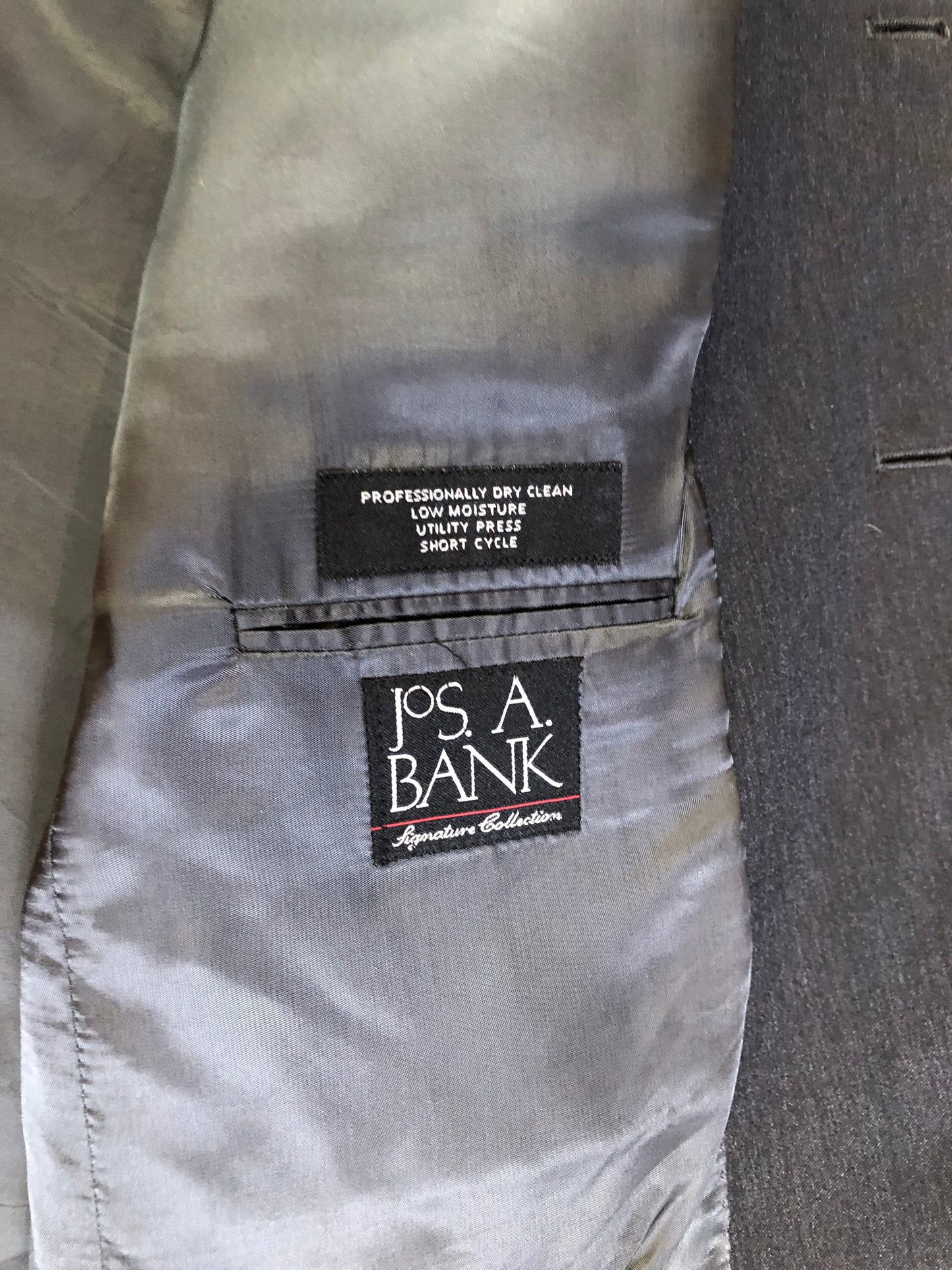 Kingspier Vintage - JoS. A. Bank, Signature Collection dark grey 100% wool two piece suit. Made in Mexico. Jacket is a three button notch lapel with two flap pockets and a breast pocket, three inside pockets and one coin pocket. Pants are pleated and cuffed with welt pockets in front and back and suspender buttons.