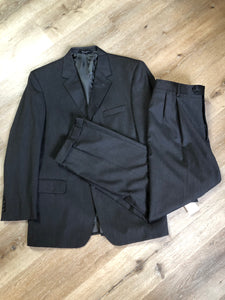 Kingspier Vintage - JoS. A. Bank, Signature Collection dark grey 100% wool two piece suit. Made in Mexico. Jacket is a three button notch lapel with two flap pockets and a breast pocket, three inside pockets and one coin pocket. Pants are pleated and cuffed with welt pockets in front and back and suspender buttons.