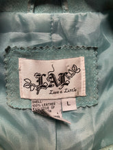 Load image into Gallery viewer, Kingspier Vintage - LAL “Live A LIttle” light teal suede jacket with hidden hook closures, brass grommets running down the front, two zip slash pockets and a small belt at the back. Size large.
