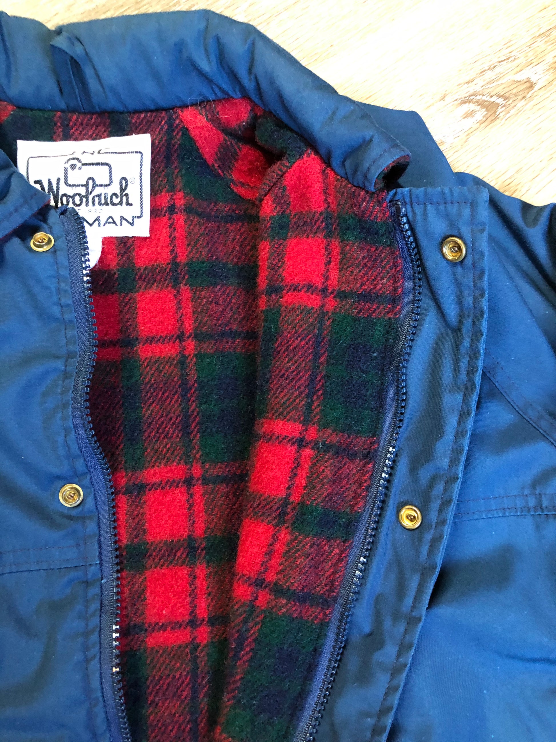 Kingspier Vintage - Woolrich Woman navy jacket with raglan sleeves, hood, zipper, snap closures with sheep logo, two flap pockets, drawstring at waist and red plaid wool lining. Made in the USA. Size medium. 