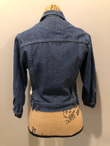 Kingspier Vintage - Guess ‘Georges Marciano’ denim jacket in a medium wash. This jacket features lavender stitching, button closures, two vertical pockets, two flap pockets on the chest and inside pockets. Made in the USA. Size small (fits very small). 
