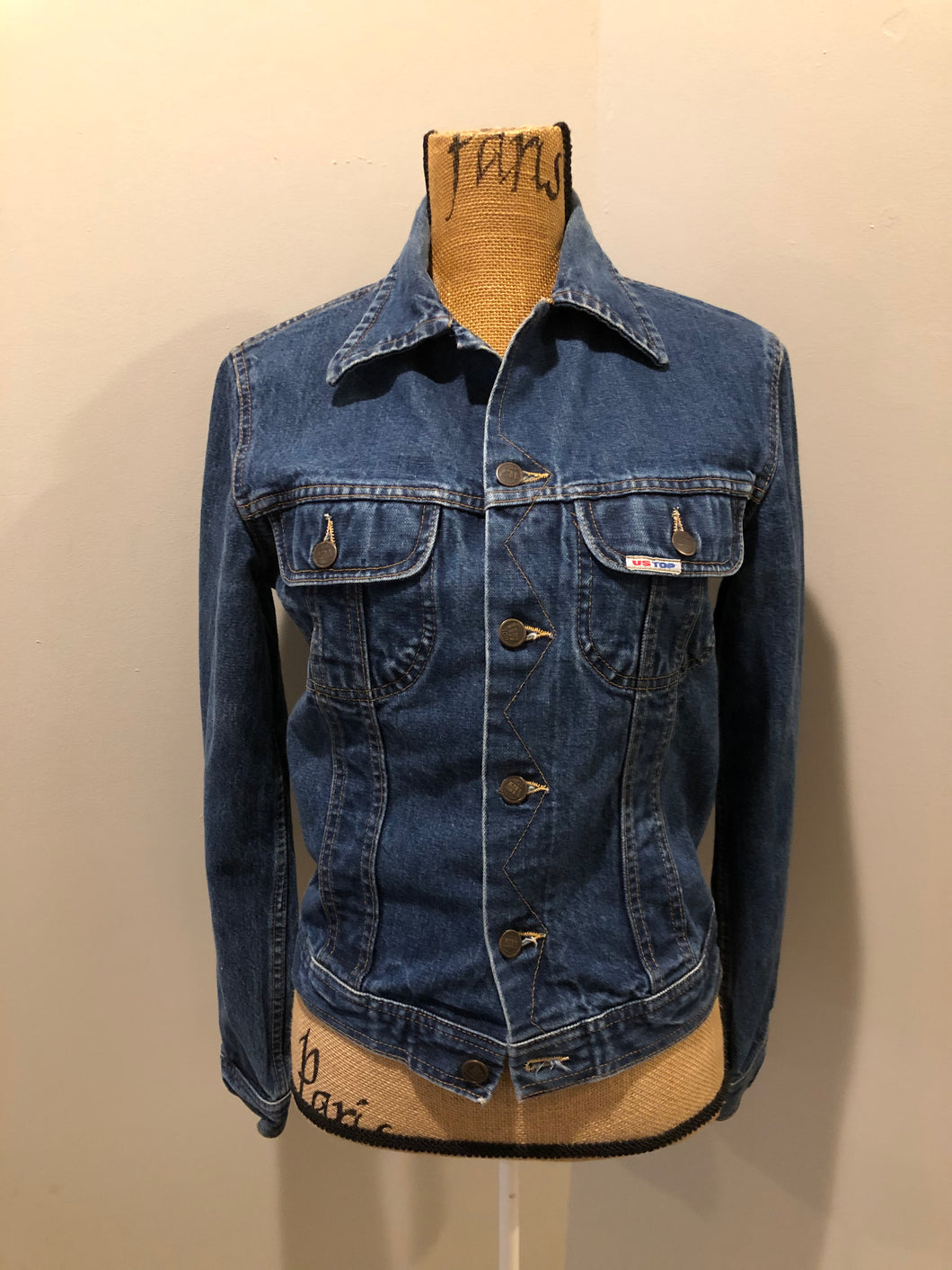 Kingspier Vintage - US Top denim jacket in a medium wash with button closures, two flap pockets on the chest, gold stitching with a unique stitch design down the center front. 