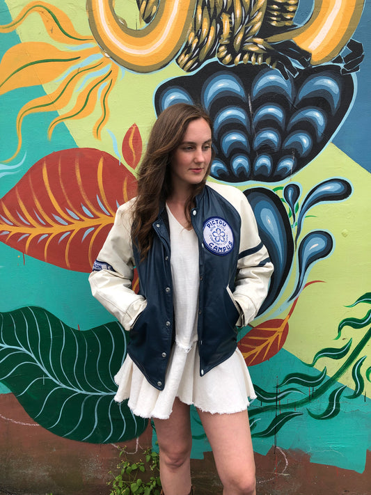 Kingspier Vintage - Vintage NSCC Pictou Campus leather varsity jacket in blue and white with snap closures, slash pockets, “Pictou Campus” embroidered on the chest, “NSCC” Embroidered on the back and “Ron” monogram embroidered on the sleeve,