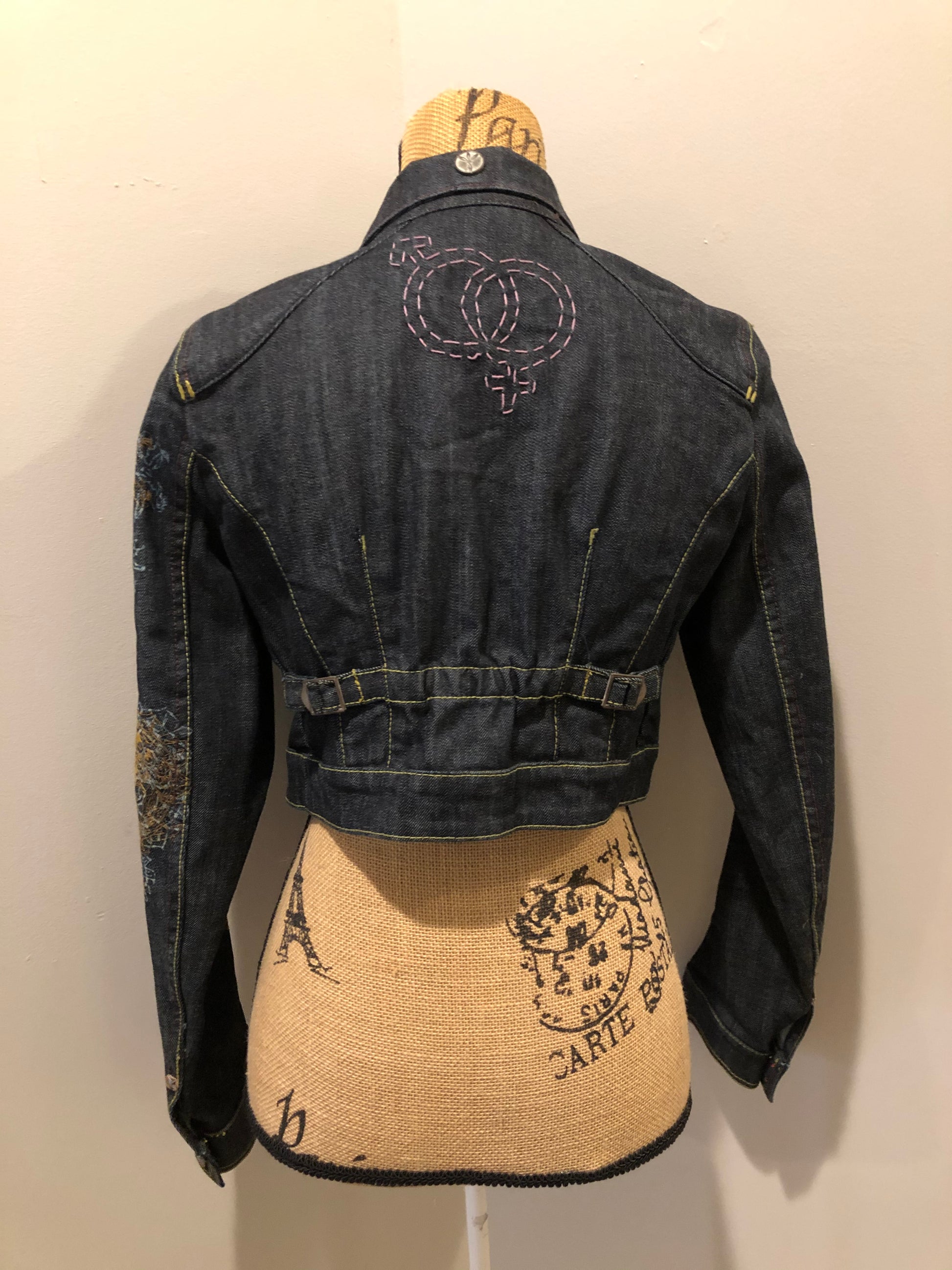 Kingspier Vintage - People for Peace cropped denim jacket in a dark wash with colourful embroidery all over, button closures, two zip pockets and two flap pockets on the chest. Size small.