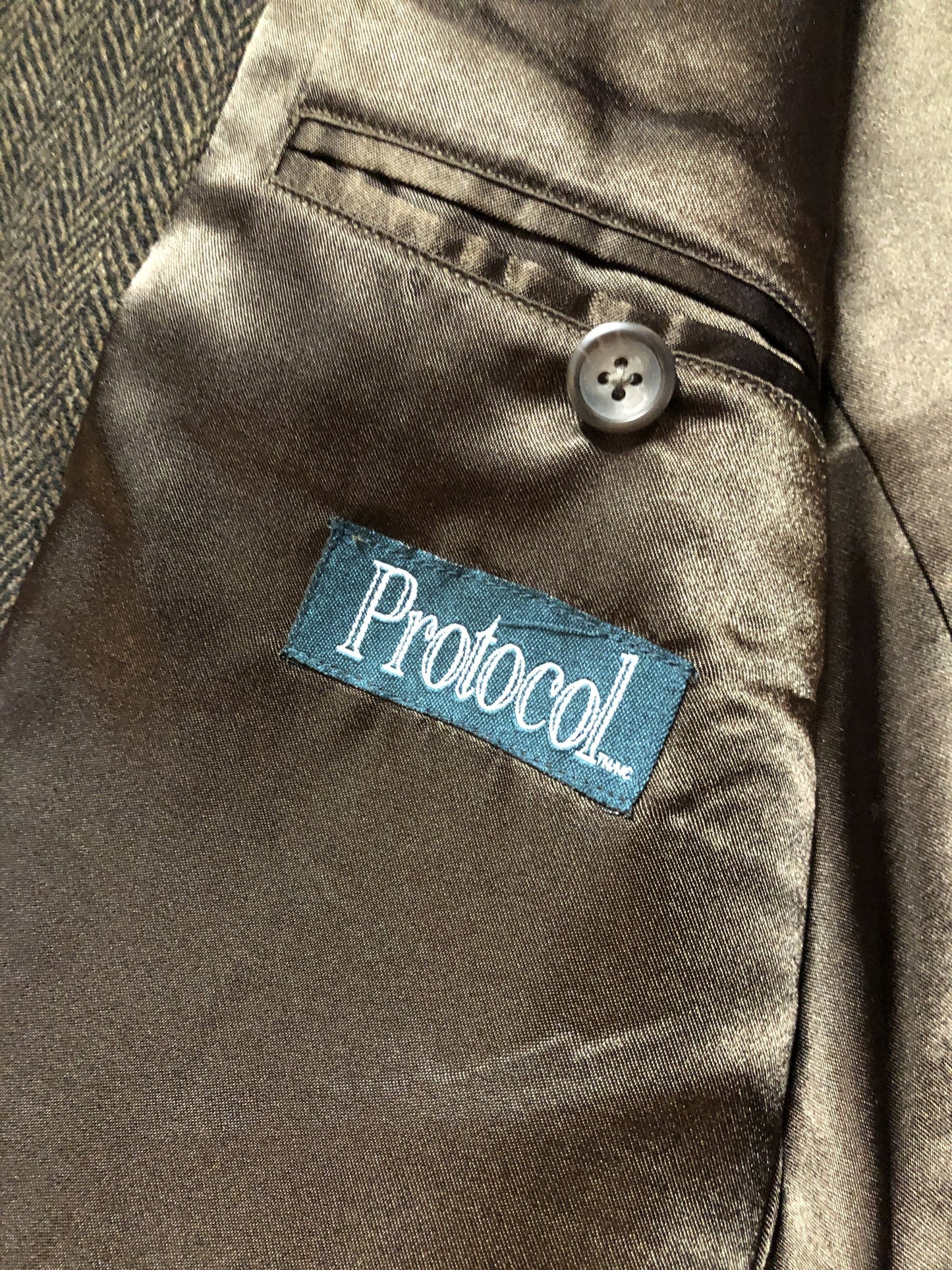 Kingspier Vintage - Protocol brown herringbone 100% pure virgin wool jacket. This jacket is a three button, notch lapel with a breast pocket, one flap pocket, one welt pocket and three inside pockets. Size 42S.