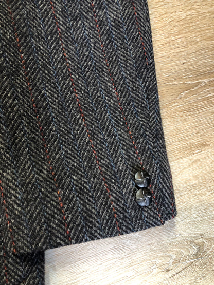 Kingspier Vintage - Harris Tweed grey herringbone with subtle red and blue stripe 100% wool jacket. This jacket is a two button, notch lapel with two patch pockets, a breast pocket and three inside pockets.