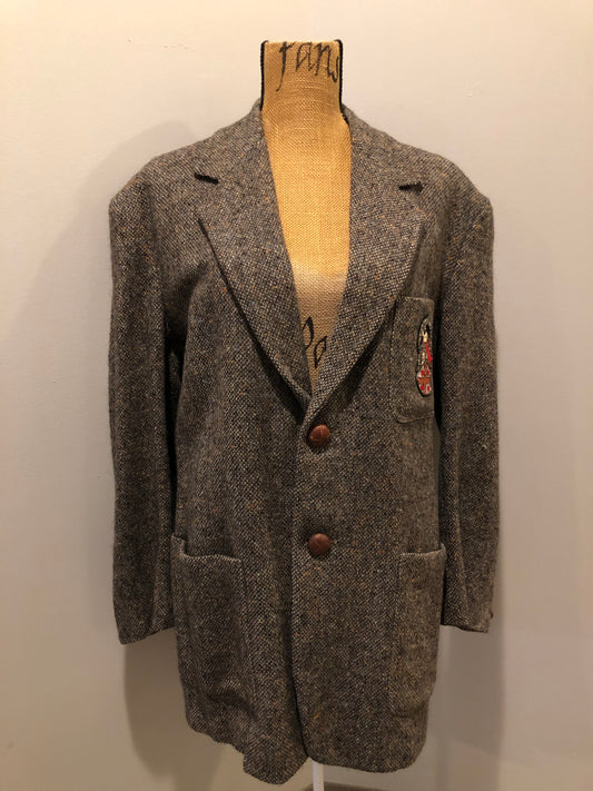 Kingspier Vintage - Donegal handwoven grey with blue and orange flecks 100% wool tweed jacket. This jacket is a two button, notch lapel with two patch pockets, a breast pocket and two inside pockets and a “this I defend” emblem embroidered on the chest. Made in Ireland.