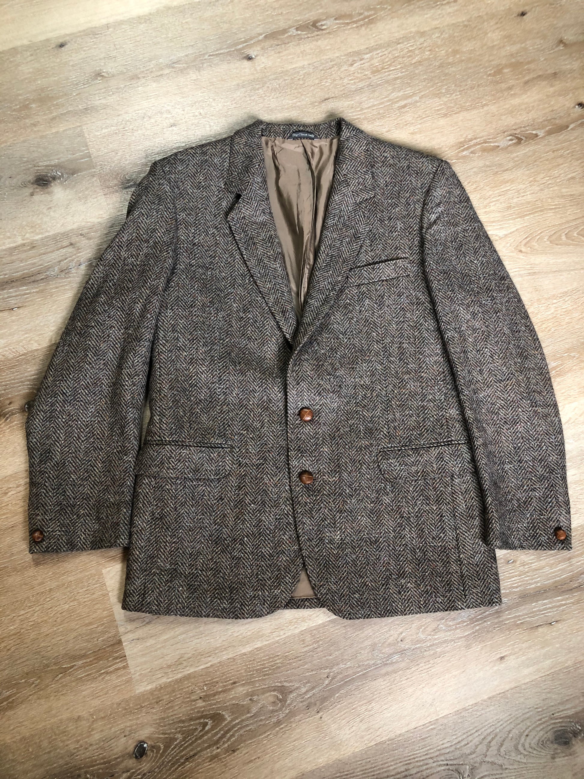 Kingspier Vintage - Paul Henry grey herringbone with flecks blue and rust 100% wool tweed jacket. This jacket is a two button, notch lapel with two flap pockets, a breast pocket and three inside pockets. Made in Europe.