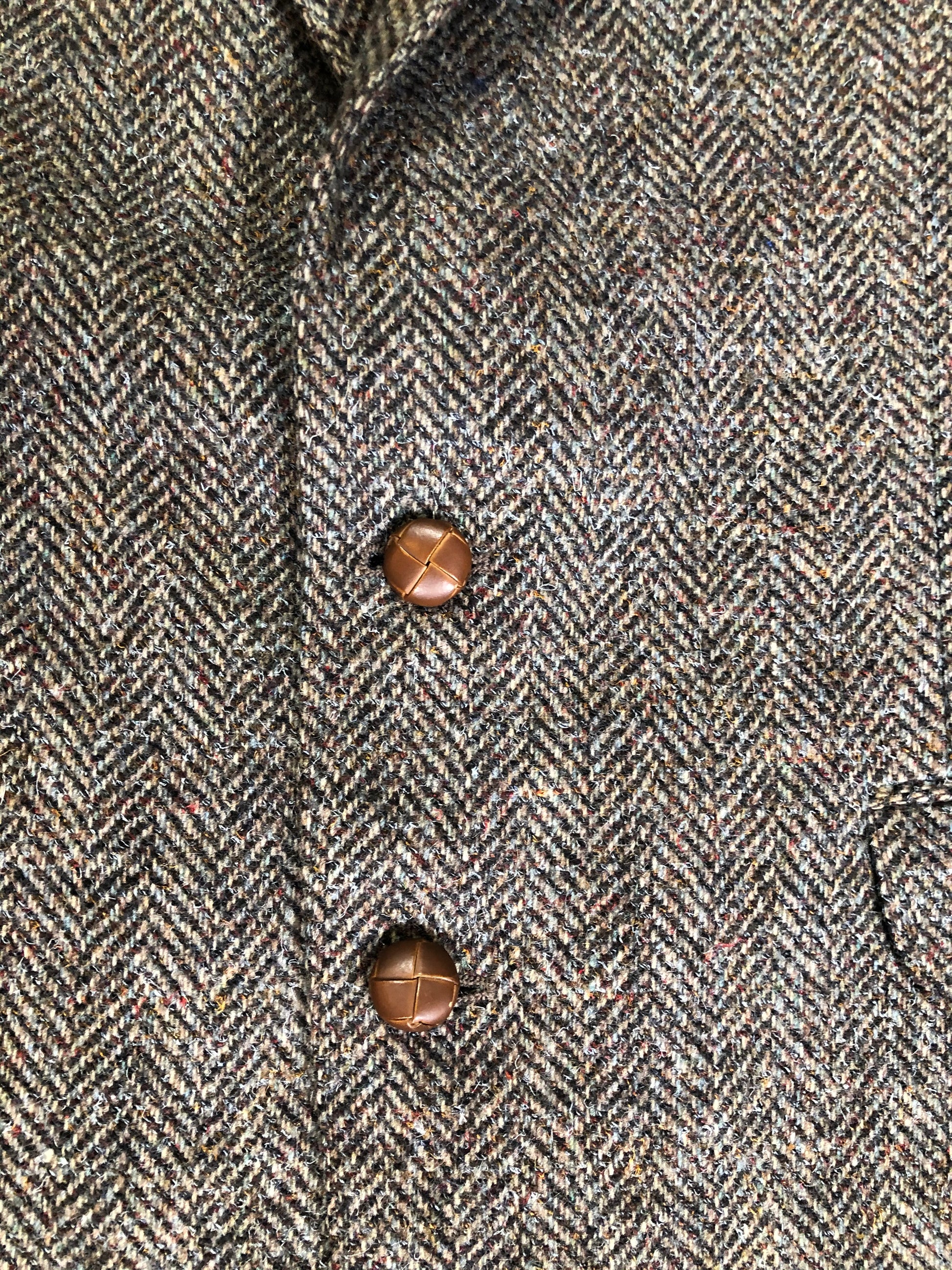 Kingspier Vintage - Paul Henry grey herringbone with flecks blue and rust 100% wool tweed jacket. This jacket is a two button, notch lapel with two flap pockets, a breast pocket and three inside pockets. Made in Europe.