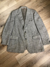 Load image into Gallery viewer, Kingspier Vintage - Morris Goldberg’s grey herringbone 100% wool tweed jacket. This jacket is a two button, notch lapel with two flap pockets, a breast pocket and three inside pockets. Made in Halifax, Nova Scotia.

