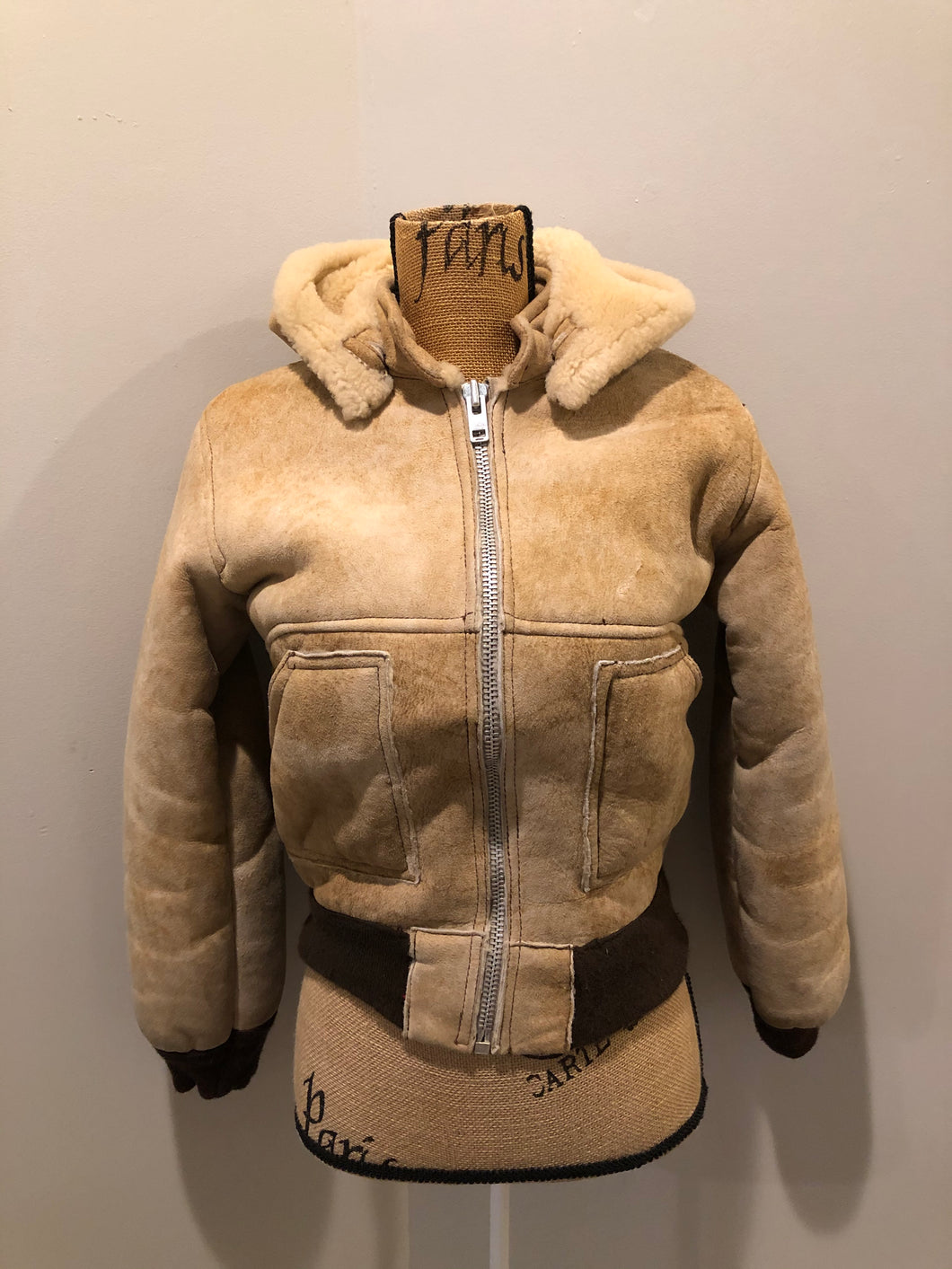 Kingspier Vintage - Ewe Wear, genuine sheepskin hooded bomber style jacket. This jacket features shearling lining, hood, zipper closure and slash pockets. Made in Kingston, Nova Scotia. Size XS.