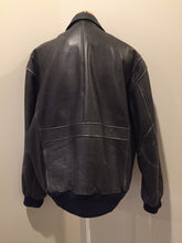 Load image into Gallery viewer, Kingspier Vintage - Black leather pilot jacket with zipper and snap closures, flap pockets, knit trim, inside pocket and plane pattern on inside lining. Size large. 
