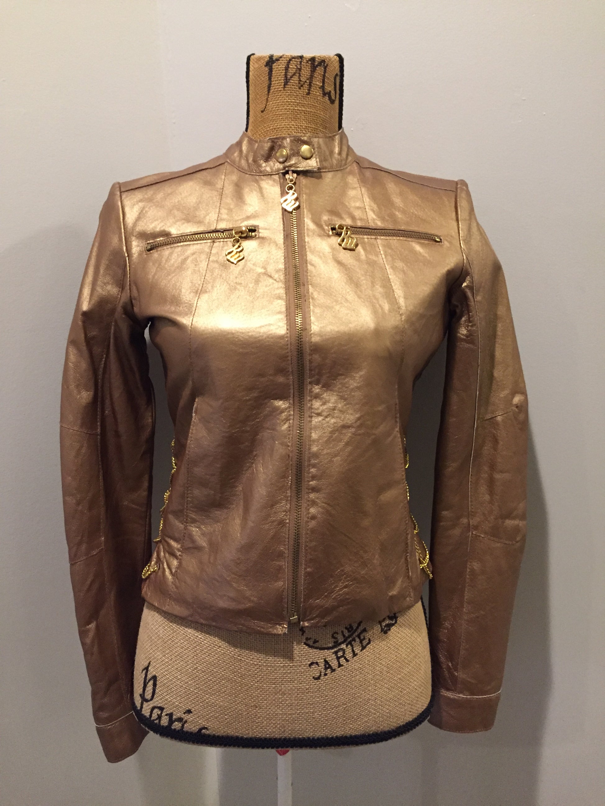 Kingspier Vintage - Rocawear metallic gold leather moto jacket with “RW” detail zippers, chain lace-up detail on sides and “ROCAWEAR” written in chain across the back. There is a front zipper, two horizontal zip pockets on the chest, two snap closures on the stand up collar and a pocket on the inside. Size small.