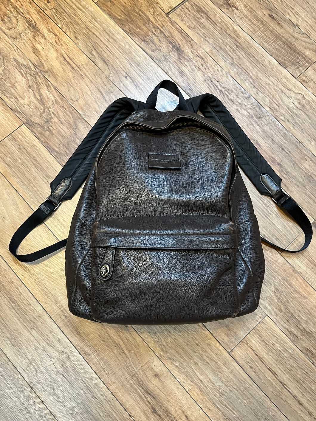 Authentic Coach brown pebble leather knapsack with adjustable shoulder straps, multiple pockets inside the large main compartment and one small compartment on the front with turn key detail.