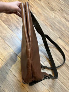 Tabique brown leather knapsack with suede lining, adjustable shoulder straps, two pockets and two pen holders inside the main compartment.