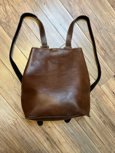 Tabique brown leather knapsack with suede lining, adjustable shoulder straps, two pockets and two pen holders inside the main compartment.