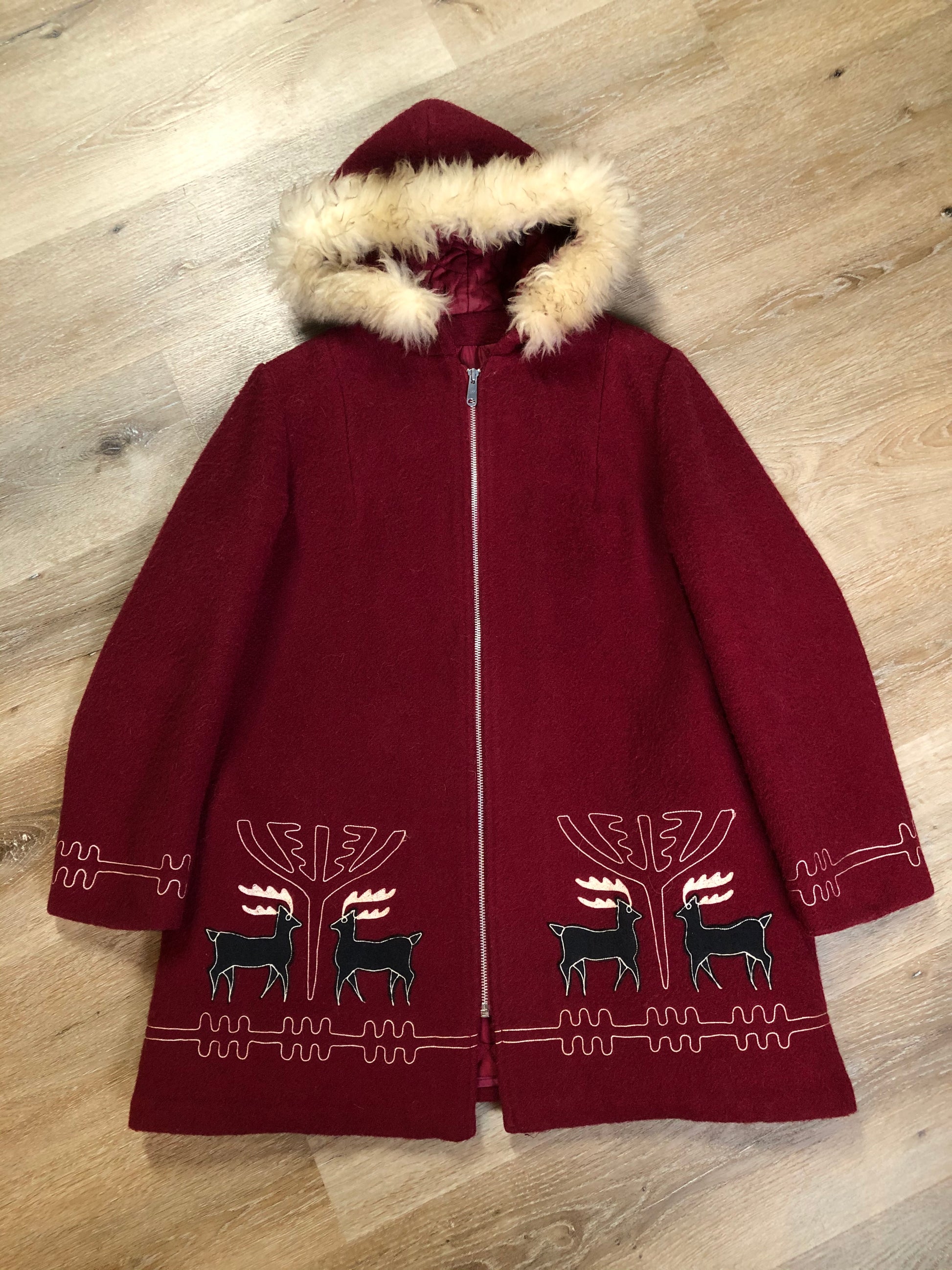 Kingspier Vintage - Sears pure virgin wool northern style parka in raspberry red. This parka features a hood with white faux fur trim, zipper closure, quilted lining, vertical pockets, hidden elastic in the lining at the wrist to keep out cold air, felt deer design appliqués on the front. Made in Canada.