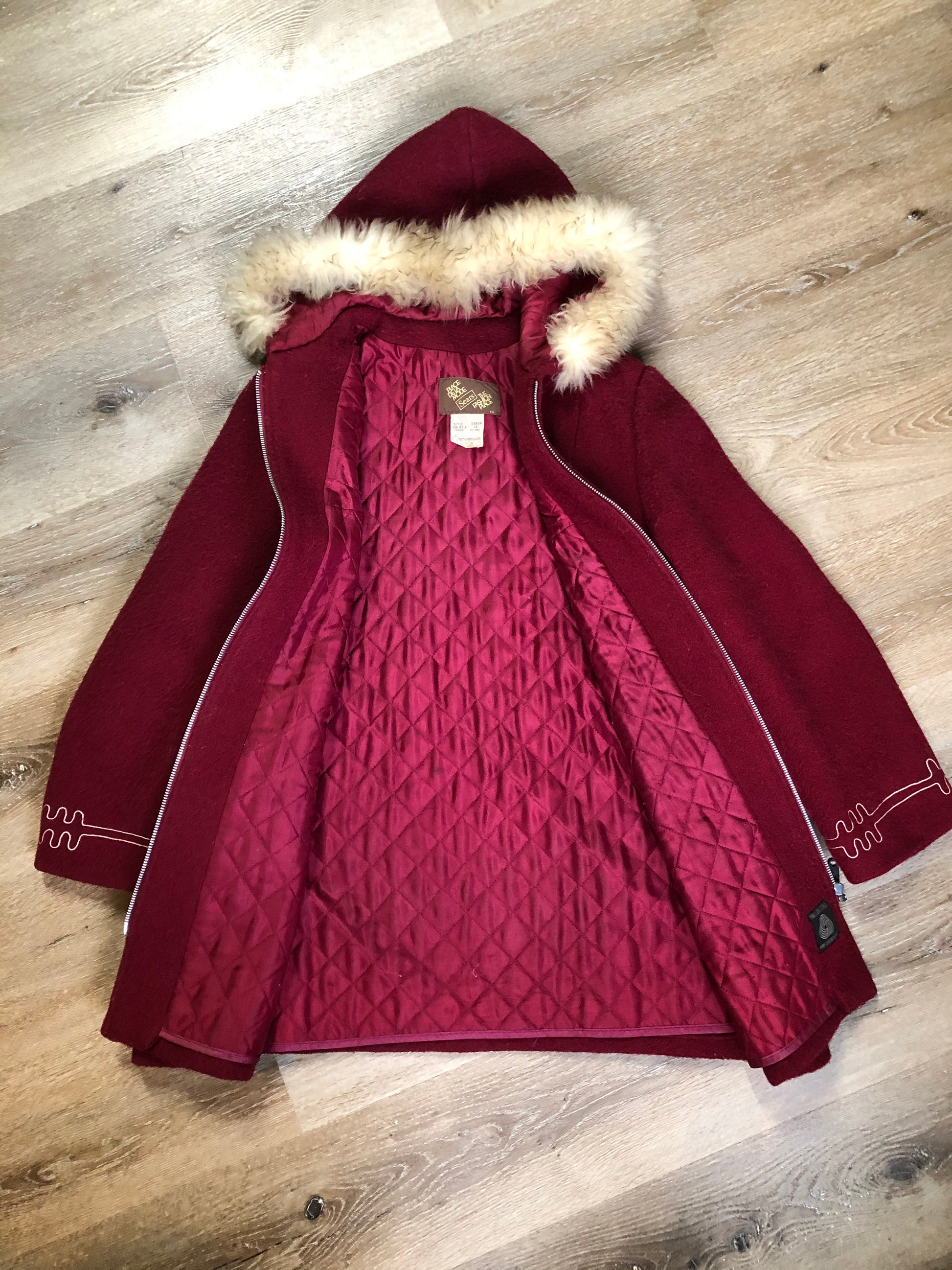 Kingspier Vintage - Sears pure virgin wool northern style parka in raspberry red. This parka features a hood with white faux fur trim, zipper closure, quilted lining, vertical pockets, hidden elastic in the lining at the wrist to keep out cold air, felt deer design appliqués on the front. Made in Canada.