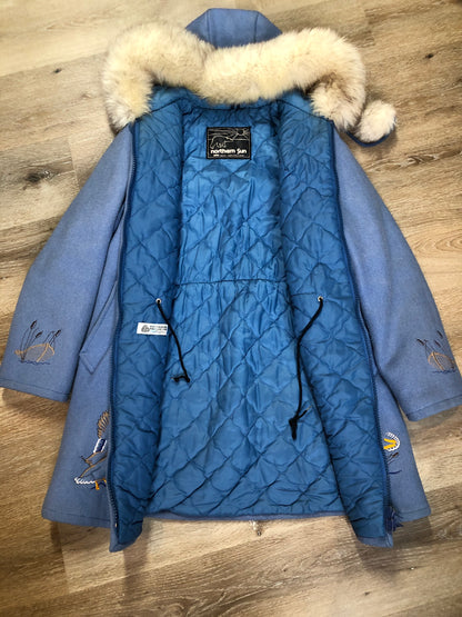 Kingspier Vintage - Northern Sun pure virgin wool northern style parka in light blue. This parka features a hood with white fur trim, zipper closure, quilted lining, slash pockets, hidden inside knit cuffs, embroidered geese design on the front and back and boats embroidered on the sleeves. Made in Canada.