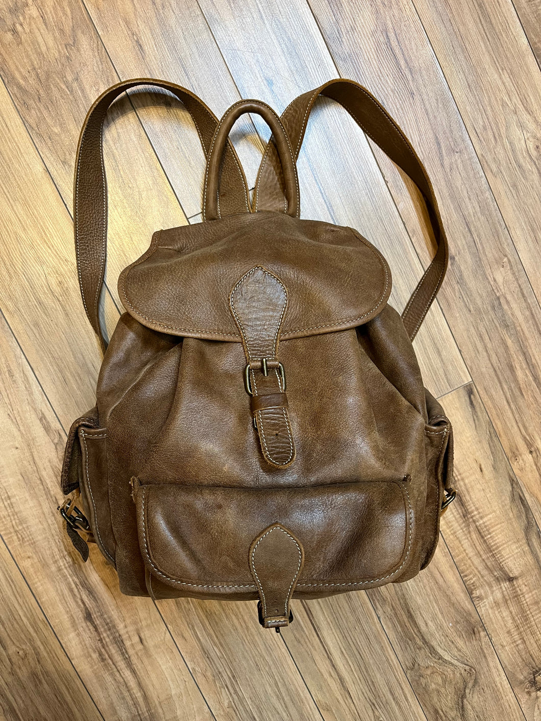 Vintage Roots Tribal Leather brown knapsack with adjustable shoulder straps, drawstring and buckle closures, one large main compartment and three small outer pockets.

Made in Canada