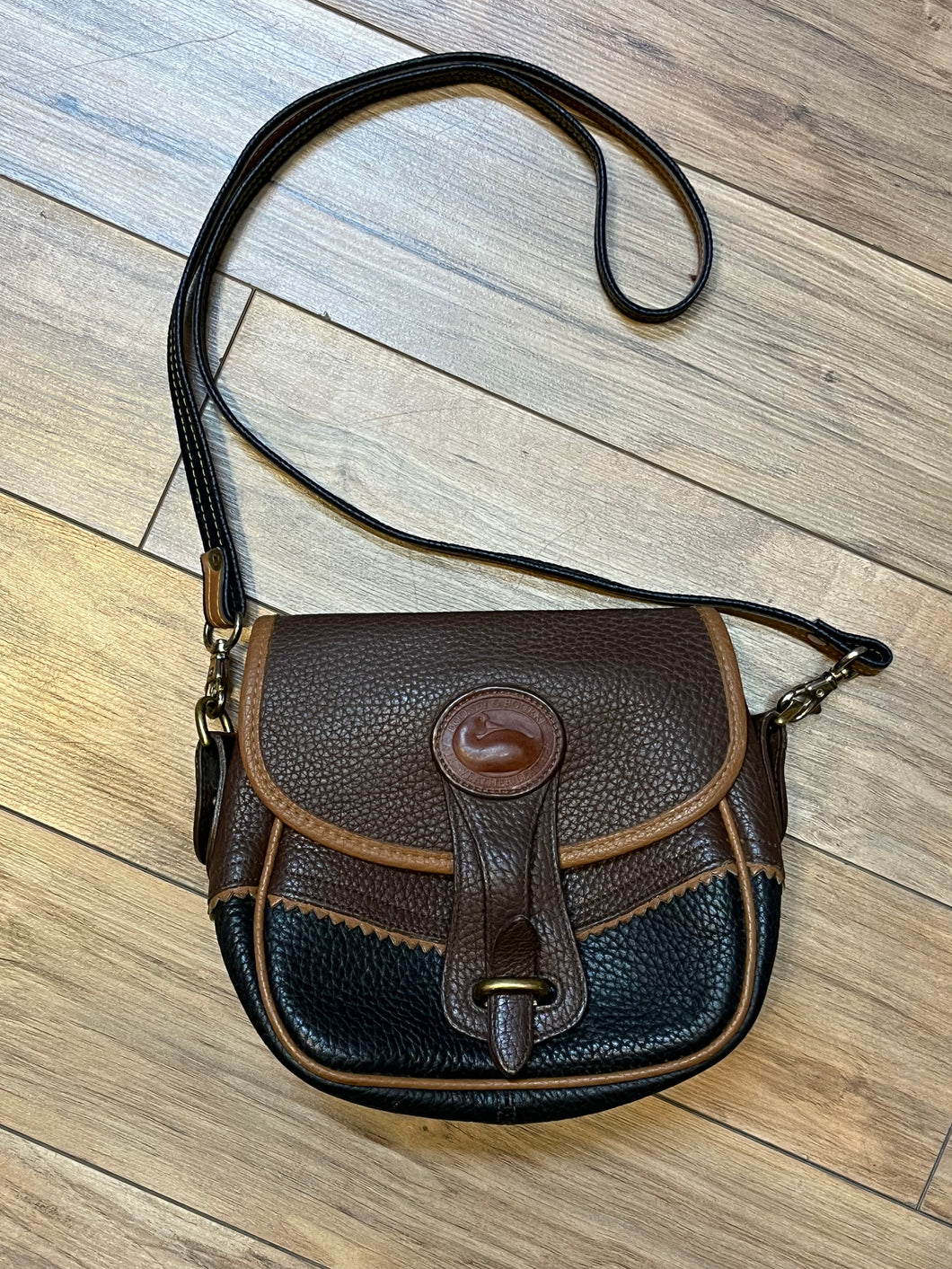 Dooney and Burke small navy and brown pebble leather crossbody bag with multiple pockets and brass hardware.