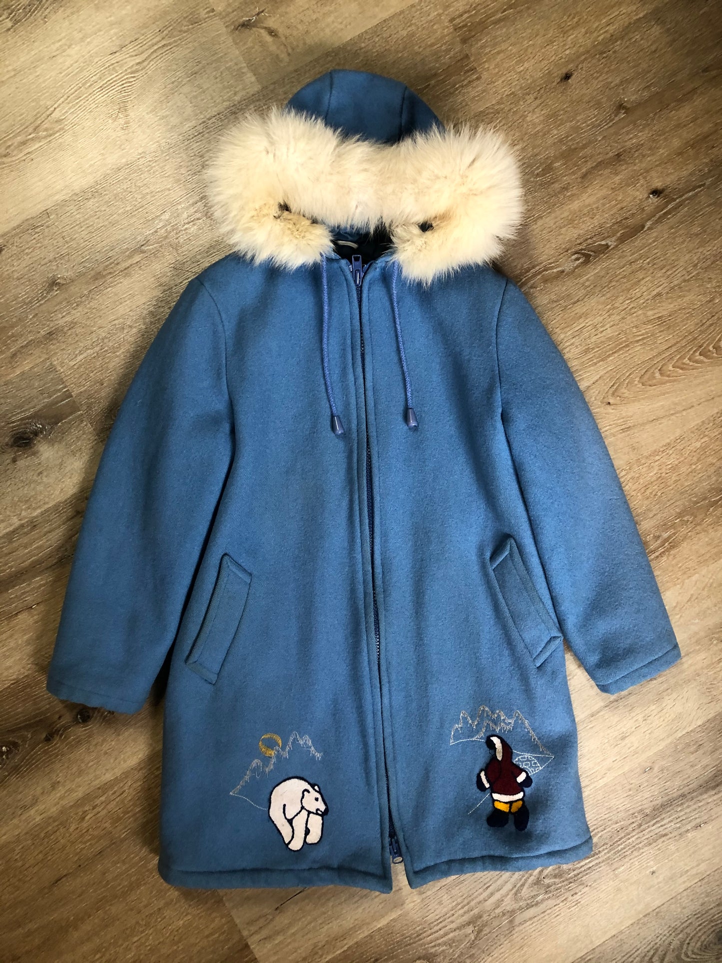 Kingspier Vintage - Northern Sun light blue pure virgin wool northern parka featuring a hood with white fur trim, zipper closure, quilted lining, slash pockets, hidden knit cuffs and arctic life design felt appliqué on the front and back. Made in Canada.