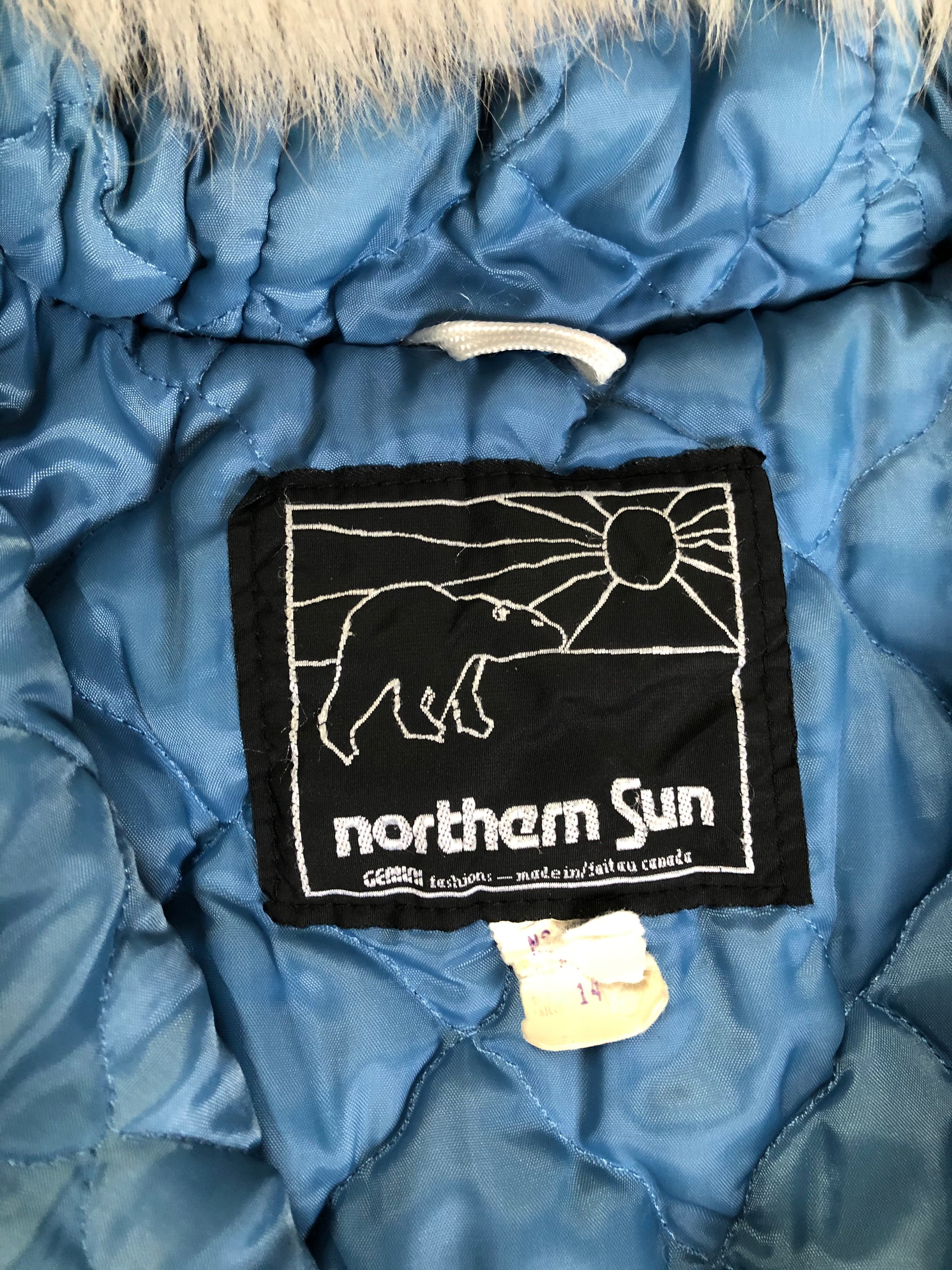 Kingspier Vintage - Northern Sun light blue pure virgin wool northern parka featuring a hood with white fur trim, zipper closure, quilted lining, slash pockets, hidden knit cuffs and arctic life design felt appliqué on the front and back. Made in Canada.