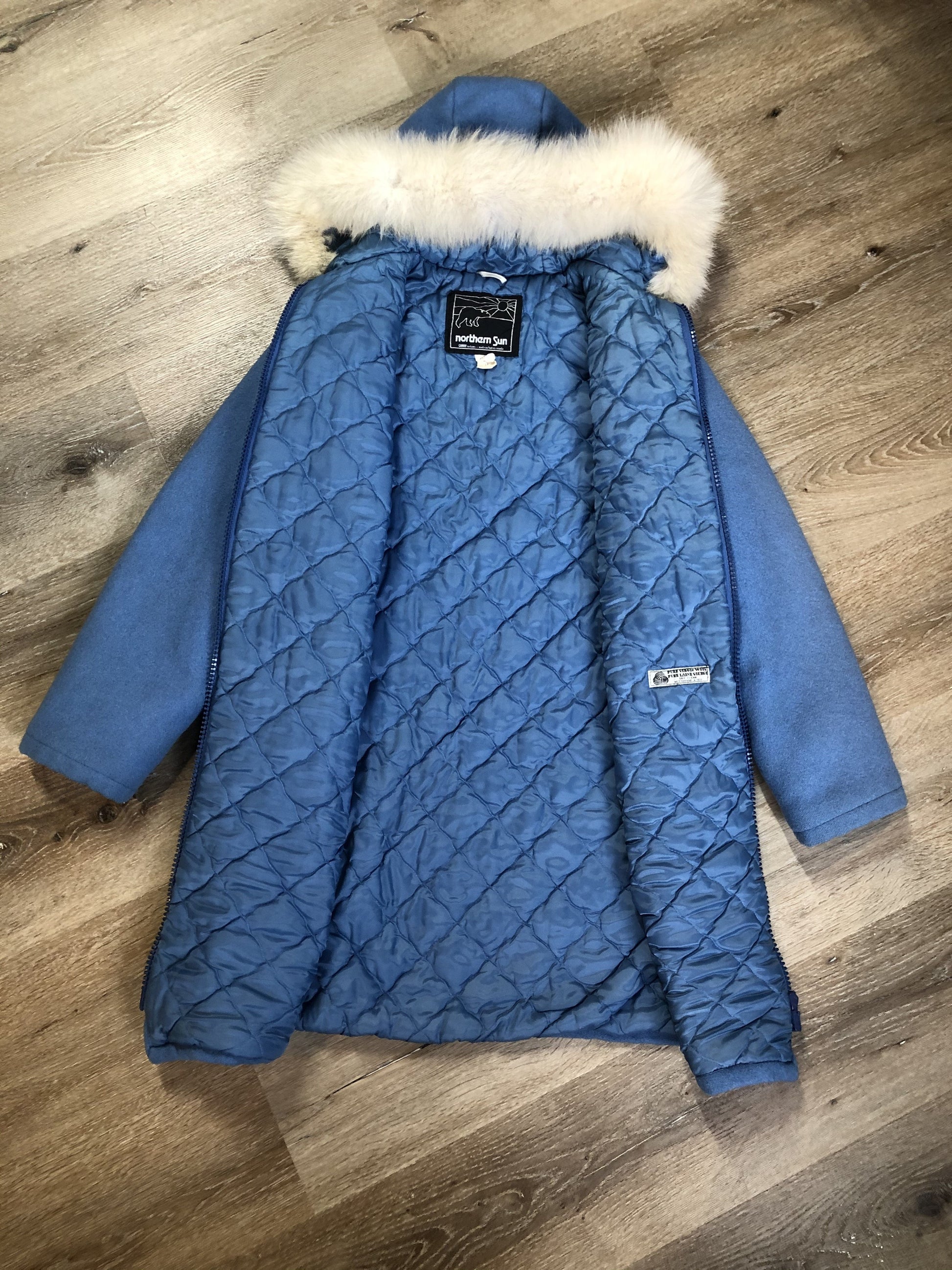 Kingspier Vintage - Northern Sun light blue pure virgin wool northern parka featuring a hood with white fur trim, zipper closure, quilted lining, slash pockets, hidden knit cuffs and arctic life design felt appliqué on the front and back. Made in Canada.