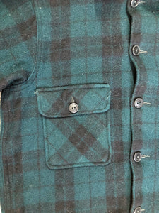 Kingspier Vintage - Woolrich dark green plaid wool lumberjack shirt with button closures and two flap pockets on the chest.