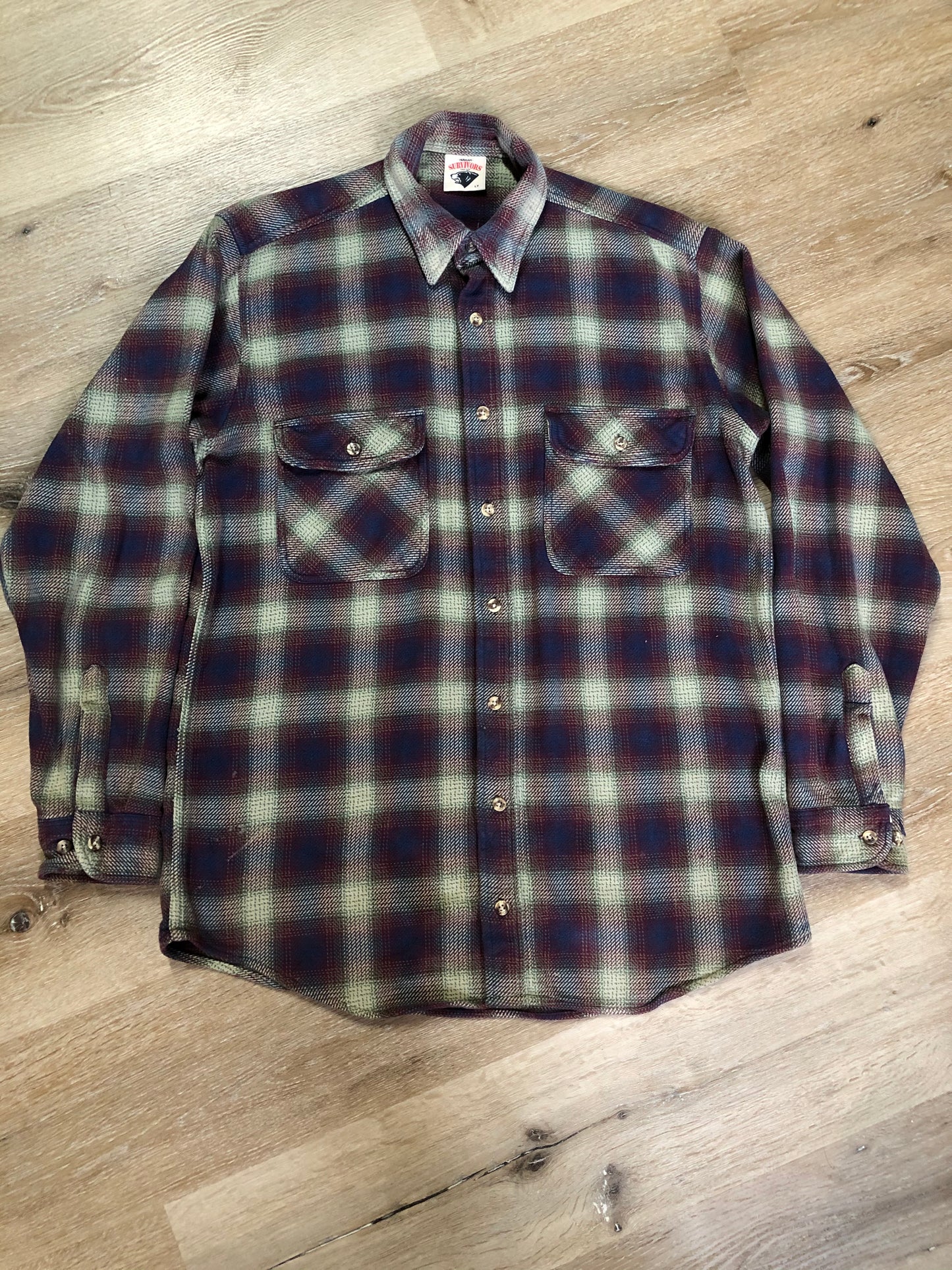 Kingspier Vintage - Herman Survivor faded blue red and green plaid lumberjack shirt with button closures and two flap pockets on the chest. Size large.