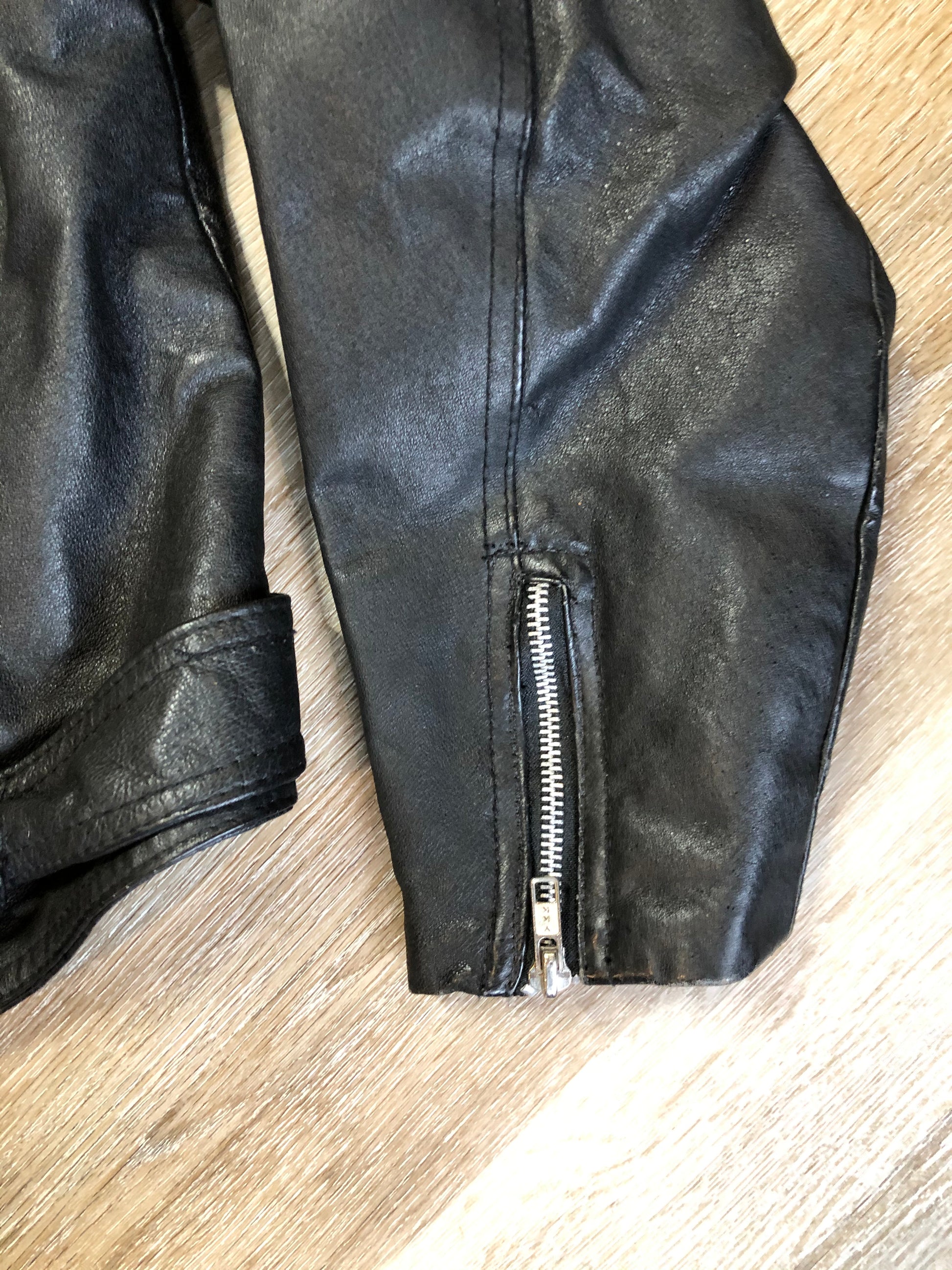 Kingspier Vintage - Cosa Nova black leather motorcycle jacket with two slash pockets, one flap pocket and a belt at the waist. Made in Canada. Size large.