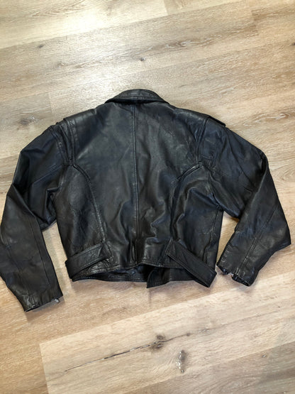 Kingspier Vintage - Cosa Nova black leather motorcycle jacket with two slash pockets, one flap pocket and a belt at the waist. Made in Canada. Size large.