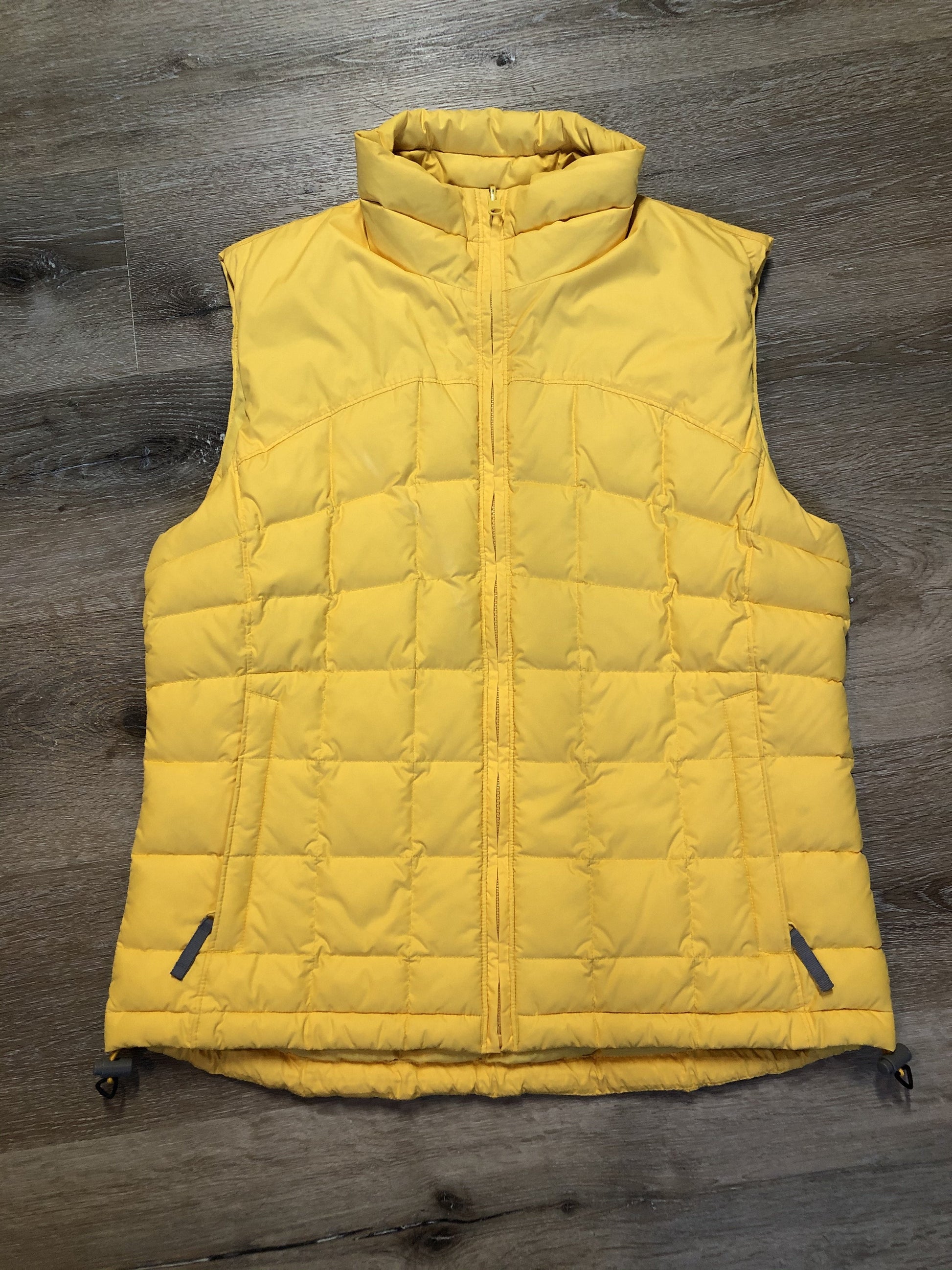 Kingspier Vintage - Columbia down filled puffer vest in yellow with zipper closure, vertical zip pockets, inside pocket and drawstring at the bottom hem. Size medium.