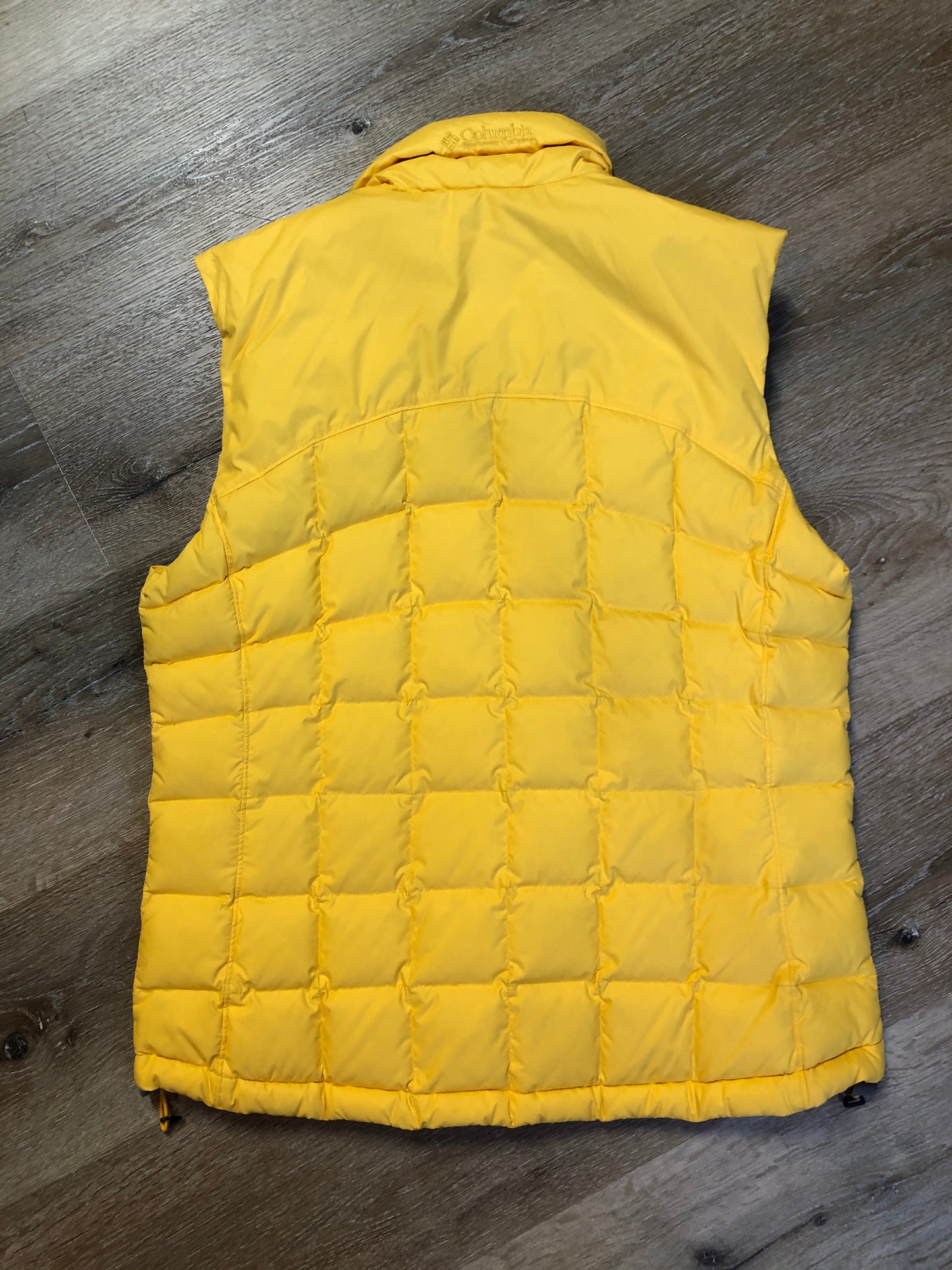 Kingspier Vintage - Columbia down filled puffer vest in yellow with zipper closure, vertical zip pockets, inside pocket and drawstring at the bottom hem. Size medium.