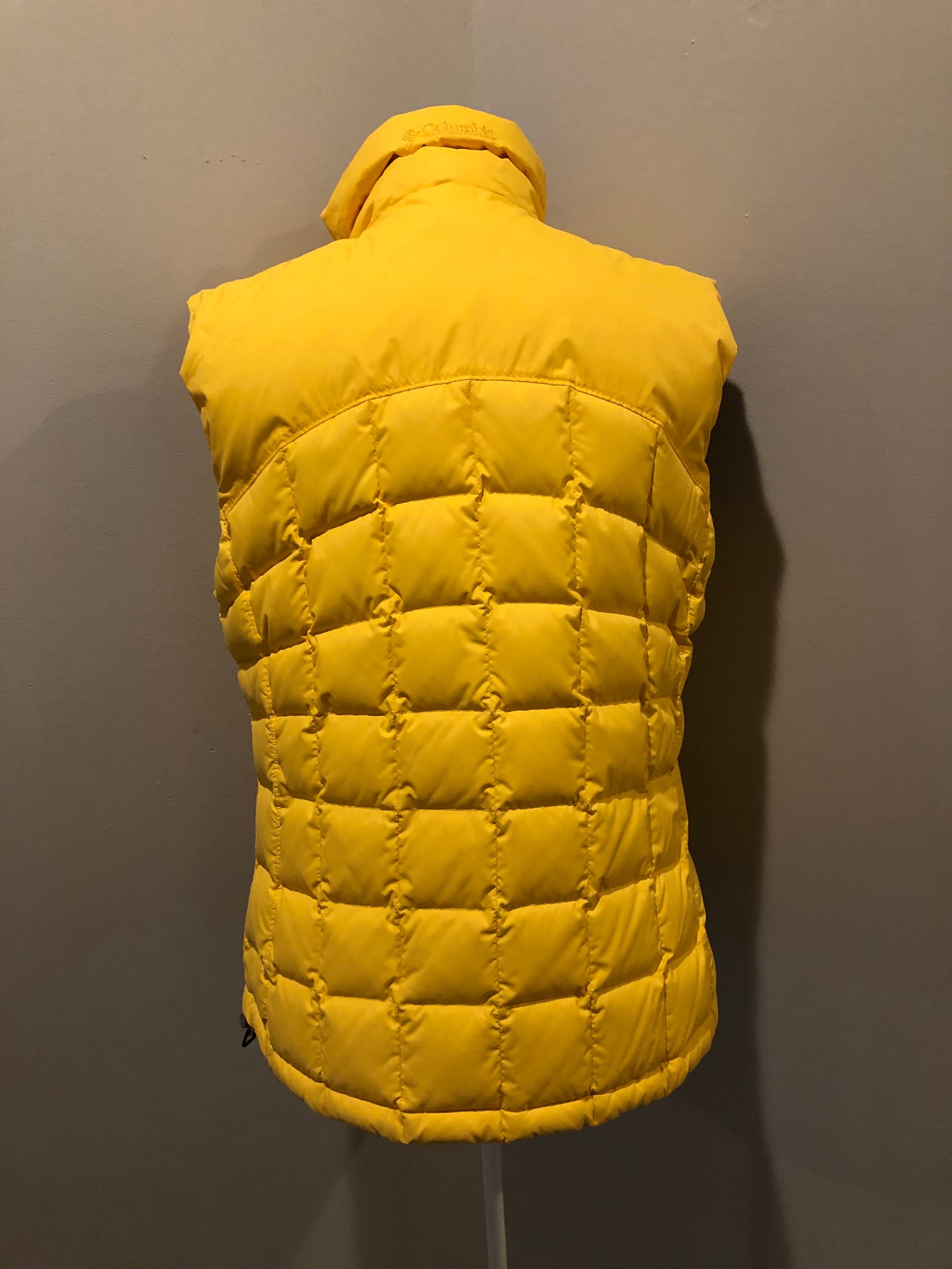 Kingspier Vintage - Columbia down filled puffer vest in yellow with zipper closure, vertical zip pockets, inside pocket and drawstring at the bottom hem. Size medium.