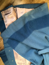 Load image into Gallery viewer, Kingspier Vintage - Hudson’s Bay Company blue and black stripe 100% virgin wool point blanket coat in a swing coat style with belt, buckle detail at the collar, button closures, slash pockets and blue satin lining. Made in England. Size large.
