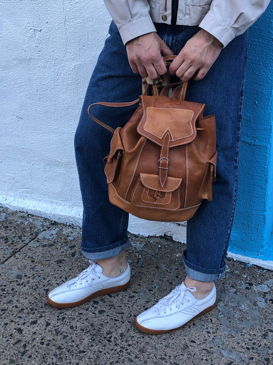 Vintage full grain leather backpack in light brown with top carry handle, flap closure, interior drawstring, three exterior compartments and adjustable shoulder straps Kingspier Vintage