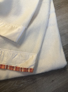 Kingspier Vintage - White 100% wool blanket with white ribbon trim on one end and a red, yellow and orange striped ribbon on the other end.
Fits a double bed.

