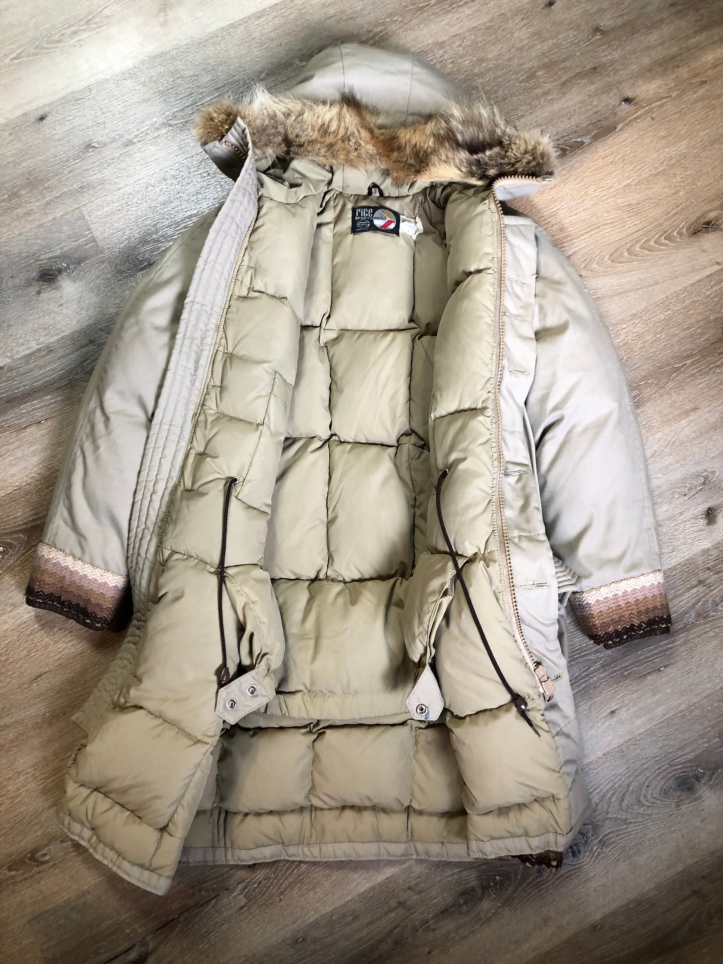 Kingspier Vintage - Vintage Rice Sportswear beige down-filled parka, with a fox fur trimmed hood. This exceptionally warm parka has embroidered ribbon detail in the cuffs and bottom hem. Parka features zipper and ribbon button closures, flap pockets and handwarmer pockets, Size medium. Made in Canada.